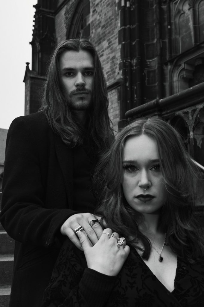 Gothic Dark Romance Paarshooting – ernster Blick, Hand auf der Schulter, dunkle Eleganz, Neografie Ruhrgebiet