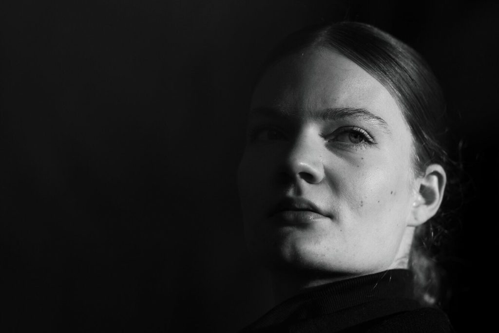 Monochrome Portrait einer Frau – minimalistisches Low-Key Licht, Gesicht tritt aus der Dunkelheit hervor, Neografie Ruhrgebiet